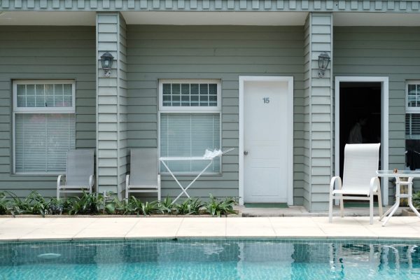 An outdoor swimming pool with white tiles surrounded by patio chairs and umbrellas